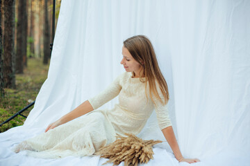 a woman in a white evening dress with sequins on a white background in the forest. dry yellow grass...