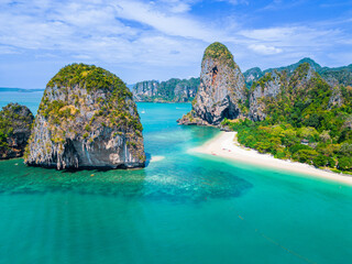 Naklejka premium Top aerial drone view of the beautiful Railay Beach in Thailand. Panoramic view of an idyllic beach with huge limestone cliffs from above, turquoise ocean, tropical island