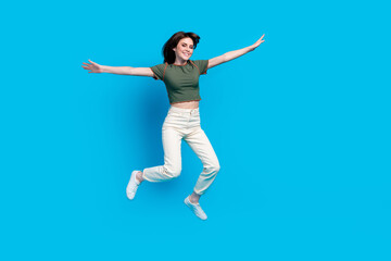Full size photo of good mood carefree woman wear green t-shirt white trousers hold palms like wings isolated on blue color background