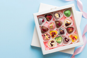 Holiday composition: sweet candy, with gift boxes with bow and chocolate hearts, photo template, background. Top View with copy space on colored background