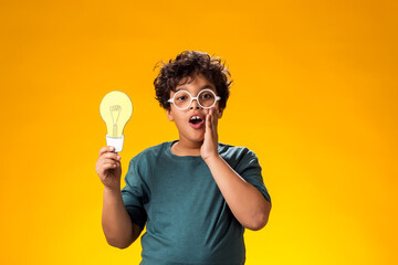 Surprised child boy holding paper bulb. Success, motivation, winner, genius, idea concept