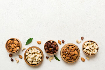 Assortment of nuts in wooden bowl on colored table. Cashew, hazelnuts, walnuts, almonds. Mix of nuts Top view with copy space