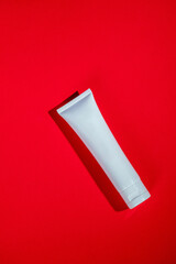 Cosmetic product in tube, bottle, lotion or serum on red background