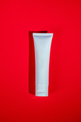 Cosmetic product in tube, bottle, lotion or serum on red background