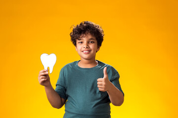 Child boy holding papercraft tooth and showing thumb up gesture. Dental health concept