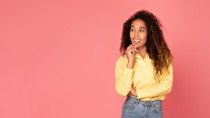 Joyful black woman touching chin, looking aside with free space on pink backdrop