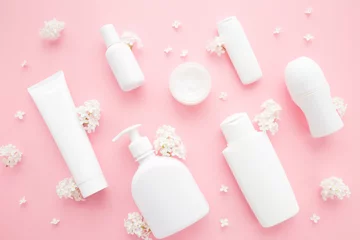 Poster Different white plastic cosmetic bottles and lilac flowers on light pink table background. Pastel color. Care about clean and soft body skin. Daily beauty product pattern. Closeup. Top down view. © fotoduets