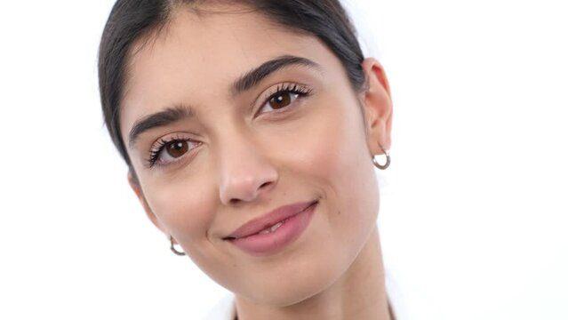 Close up portrait of a optimistic young Caucasian woman with smile looking at camera over white background. Positive, friendly expression.