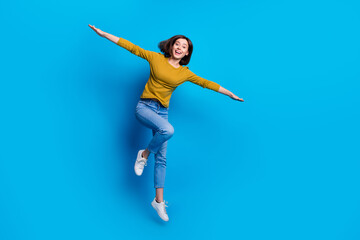 Full length photo of excited pretty lady dressed shirt flying arms sides jumping high empty space...