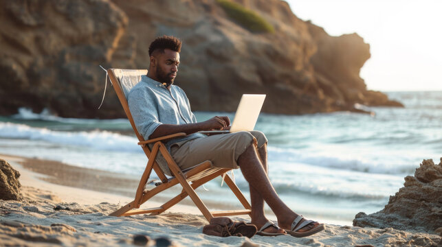 man sitting on a beach chair using a laptop by the sea