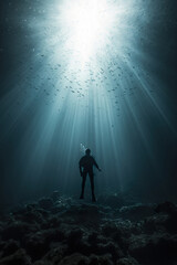 person scuba diver swimming underwater, man diving in deep blue sea or ocean