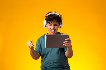 ?hild boy using digital tablet and headphones and playing video game. Leisure and gadget addiction...