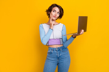 Portrait of pretty creative minded lady hold laptop finger touch chin look empty space isolated on...
