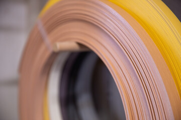 Abschlussleisten für die Kantenverleimung auf einer Rolle an der Wand einer Tischlerwerkstatt