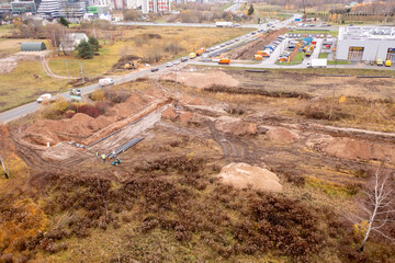 Drone photography of sewage pipe being lade down i a ditch by a road during autumn day