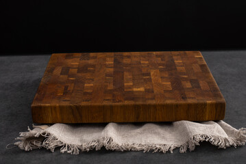 Cutting board on a grey stone table. Isolated on a black background. Culinary background. Empty wooden cutting board, product display space.