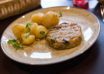 Chicken burger with boiled potatoes on plate