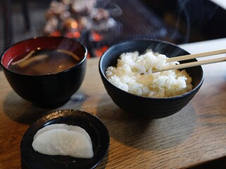 囲炉裏の前で食べる白米、たくあん、味噌汁