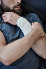 cropped view of depressed man with bandage on arm after attempting suicide, mental health awareness