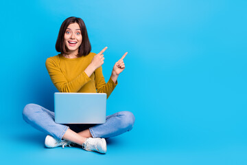 Full length photo of funky excited lady dressed shirt typing modern gadget pointing two fingers empty space isolated blue color background