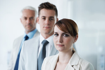 Portrait of three corporate business people , standing in a row and in broad room. Smiling friendly group of three business partners of different age private company staff posing for office
