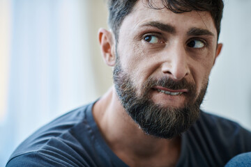 Fototapeta premium ill traumatized man with beard biting his lips during depressive episode, mental health awareness