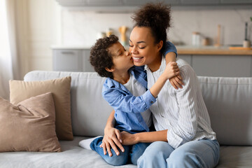 Preteen boy gives loving kiss on the cheek to his joyful mother