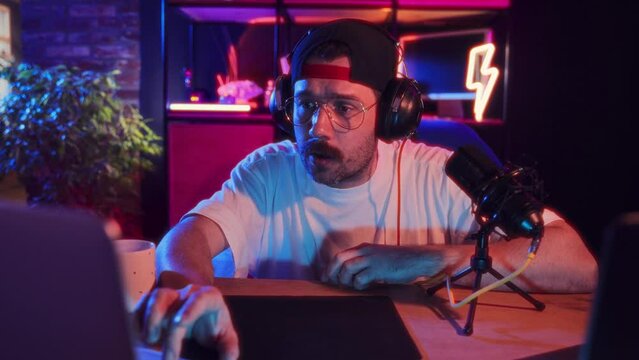 Man sitting at home in headphones, playing online video game, gamin tournament with online team. Communication. Concept of blogging, online services, streaming, education