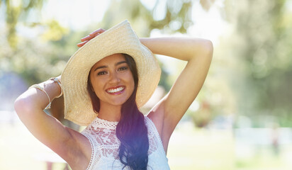 Woman, portrait and hat for relaxing in park or garden, smiling and joyful on summer holiday. Female person, peace and enjoy vacation in countryside, outdoors and calm on weekend adventure in nature
