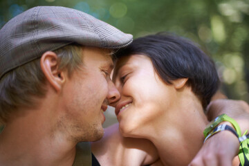 Fototapeta premium Couple, closeup and embrace outdoors for date with wristband for festival, concert or adventure together. Man, woman and smile with flat cap for summer in nature, forest or woods with happiness