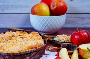 Freshly baked apple pie on a rustic kitchen worktop with ingredients and kitchen utensils.