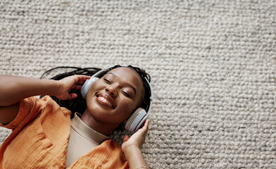 Home, music and black woman on a couch, headphones and streaming audio in a living room. African...
