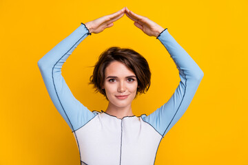 Photo of cheerful positive woman wear top smiling showing arms roof isolated yellow color background