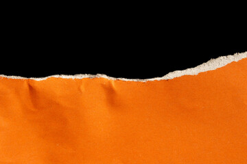 Ripped orange paper isolated on black background. Torn paper with space.