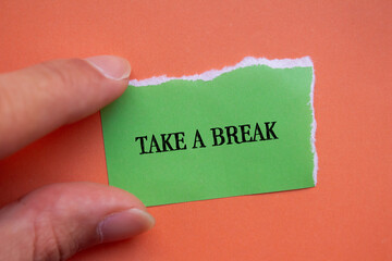 Take a break lettering on ripped green paper piece with orange background. Conceptual photo. Top view, copy space for text.