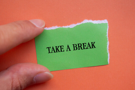 Take a break lettering on ripped green paper piece with orange background. Conceptual photo. Top view, copy space for text.