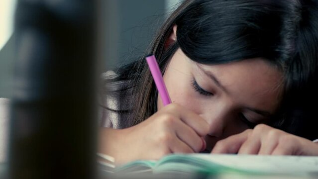 Concentrated child drawing on paper with coloring pen, tight close-up face of little girl engaged in artistic play