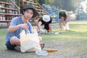 Group of asian teenboys doing the volunteer at the park of their village by picking up bottles,...