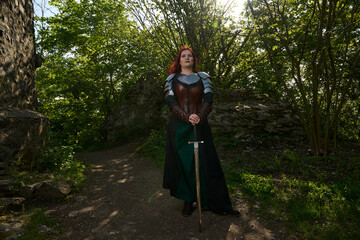 Mittelalterliche Frau mit Rüstung und roten Haaren als Kriegerin mit Kriegsbemalung mit Schwert im...