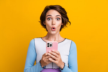 Photo of cheerful excited woman wear top getting emails modern device isolated yellow color...