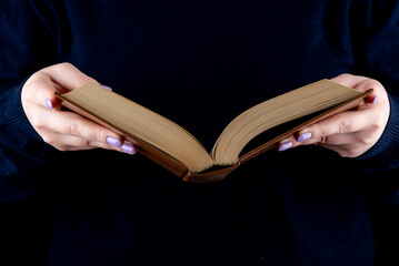An open book in hardcover in female hands with a fashionable manicure.