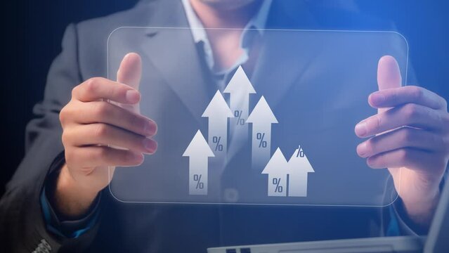 On the transparent screen of the electronic tablet, the arrows move upwards with the designation of percentages. The tablet is demonstrated by a man in a business suit. Cg