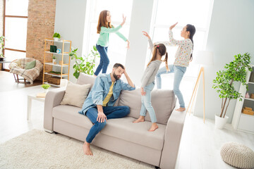 Full length photo of four people minded guy sit on couch arm on head funny girls standing give high...
