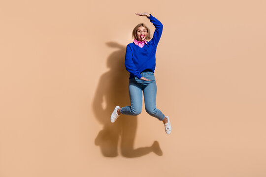 Full body length photo of measure size height funny woman in formal wear jumping gesture her size isolated on beige color background