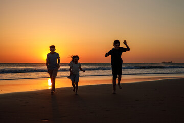 Portrait of three children, happy kids on beach at sunset. happy family, two school boys and one little preschool girl. Siblings having fun together. Bonding and family vacation