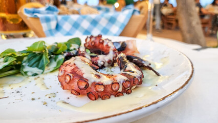 Closeup of a grilled octopus dish in a Greek taverna restaurant. - obrazy, fototapety, plakaty
