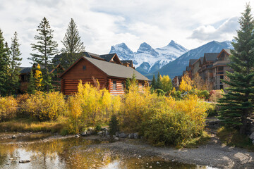 Fototapeta na wymiar Town of Canmore in autumn. Alberta, Canada. Canmore Opera House at Spring Creek. The Three Sisters trio of peaks in the background.