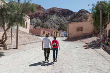 Enamorados seniors de la mano caminando por poblado en el norte de argentina, Jujuy, Cerro de siete...