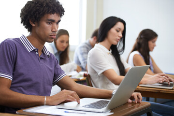 University, laptop and man in classroom typing with research, learning and future opportunity. Education, knowledge and computer with group of students in college lecture studying for online exam.