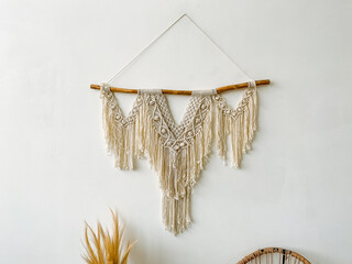 White wall adorned with macrame wall hanging, twig, plant, art, jewellery, wood, font; rectangular metal frame, houseplant event.